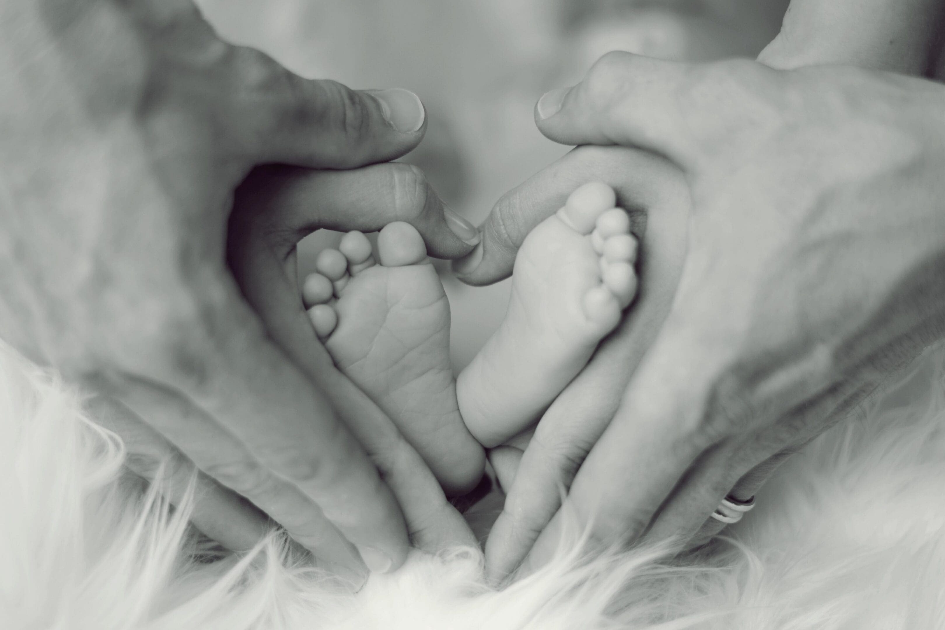 Newborn infant cradled in a parent's hands, illustrating rachamim — the Hebrew word for womb-deep compassion in Isaiah 49