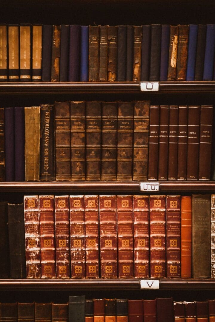 Rows of antique leather-bound books on wooden library shelves, evoking the Oxford rooms where C.S. Lewis studied and read.